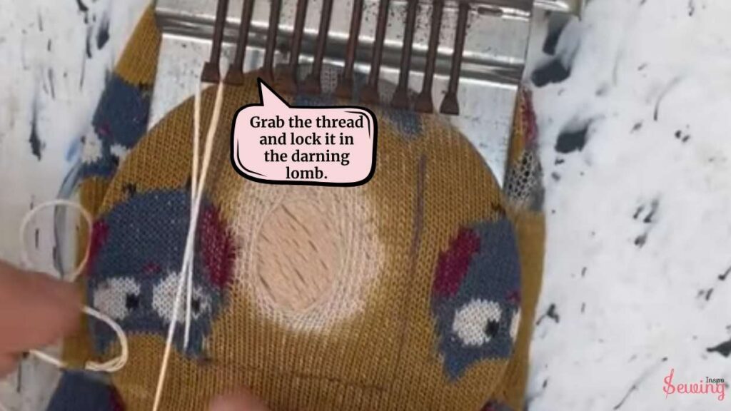 grab the thread and lock it in the darning lomb